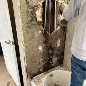 A man removing mold-contaminated drywall