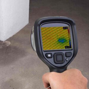 An image of a technician performing water damage assessment with a FLIR Camera