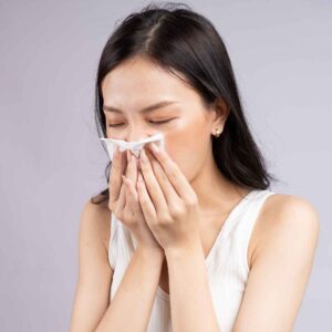 A woman sneezing. How to tell if your indoor air quality is making you sick.